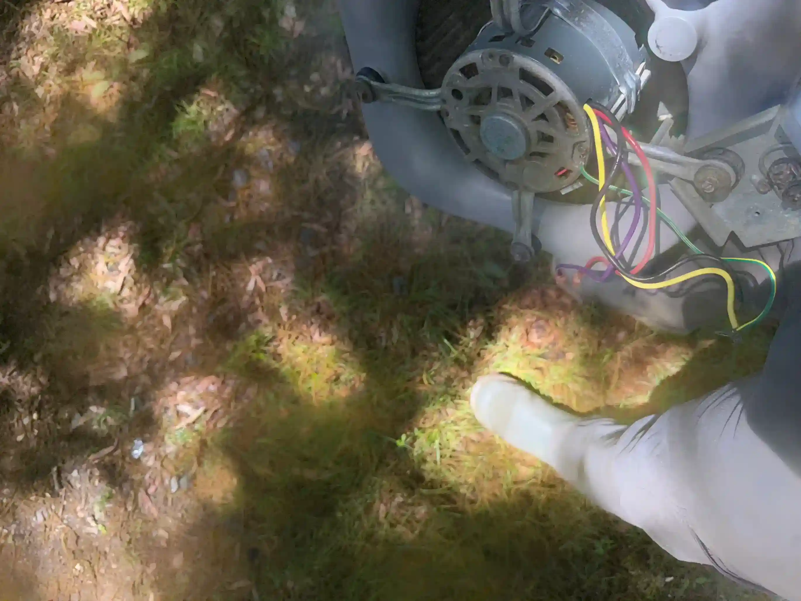Technician examining blower motor lead connections at junction block
